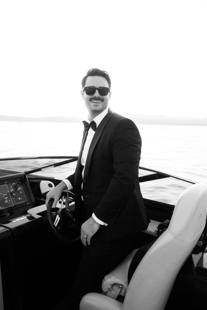 Candid, cinematic moment of the groom steering a private boat on Lake Garda