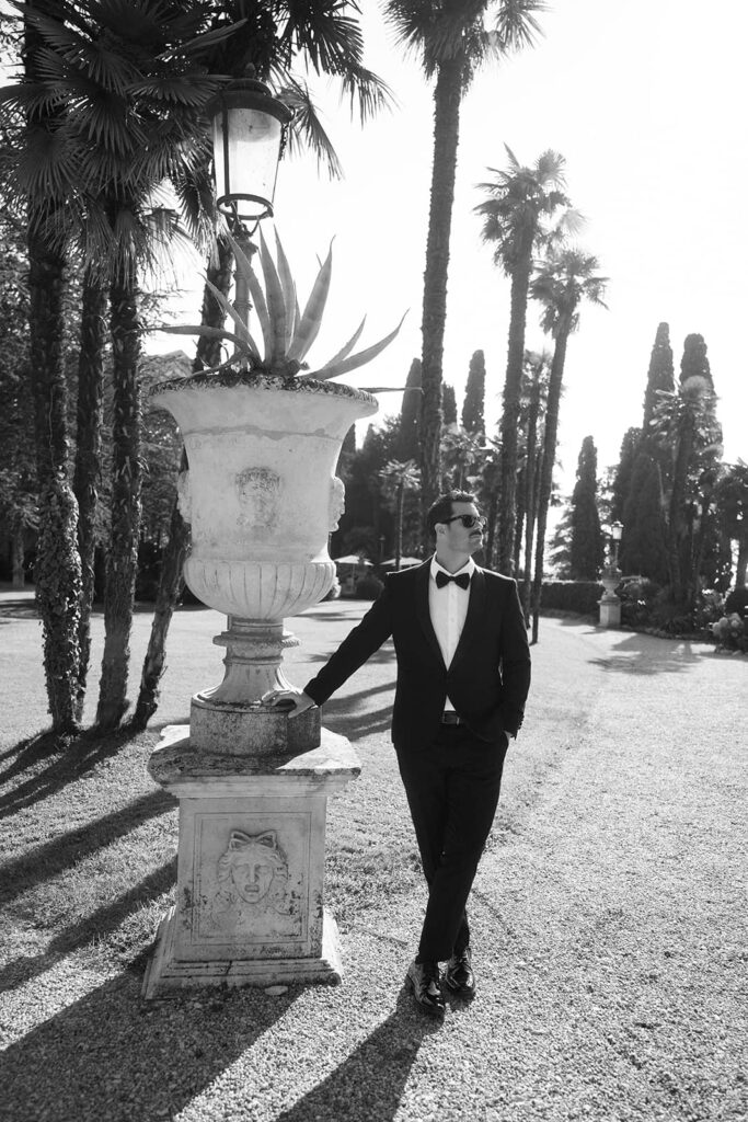 Timeless black-and-white portrait of the groom walking through Isola del Garda’s Italian gardens